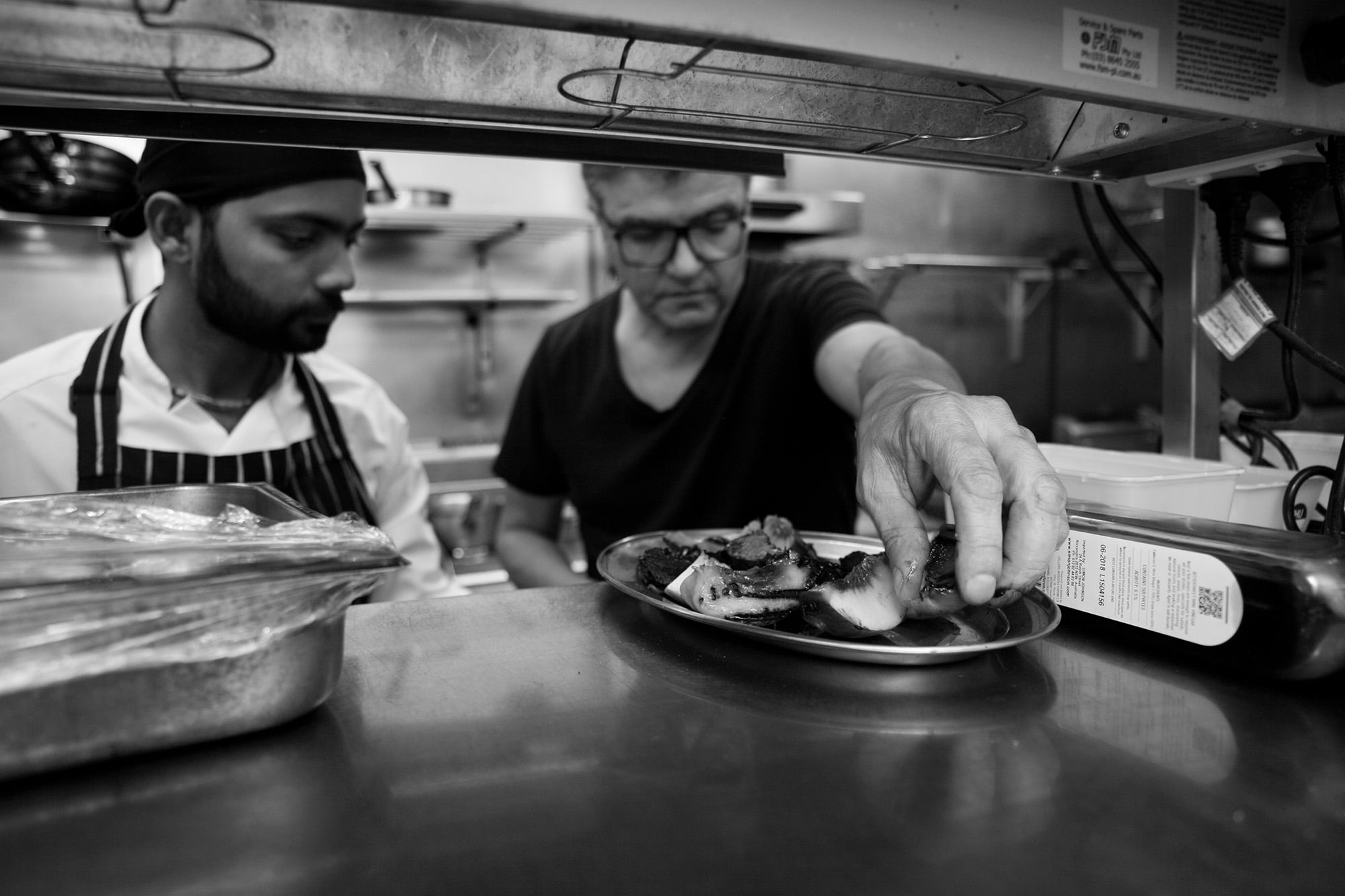 Chef in black carefully plating a dish