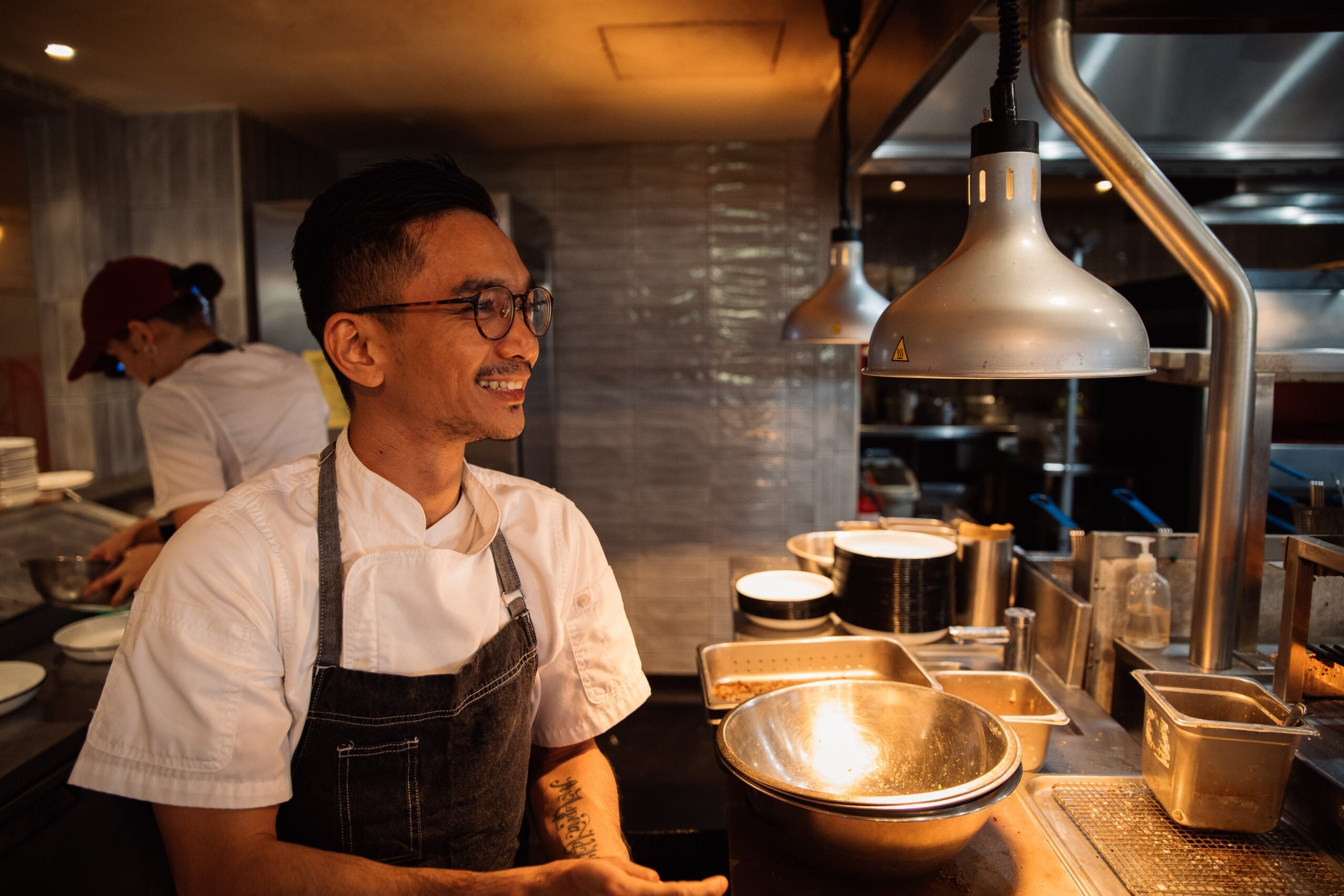 Smiling chef working at a warm restaurant counter