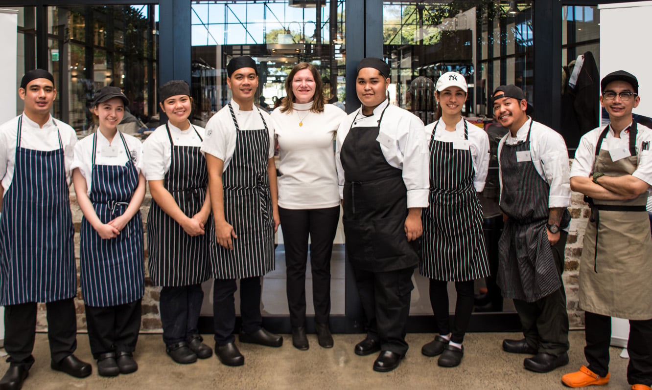 Celine Davenport with a line-up of chefs in aprons